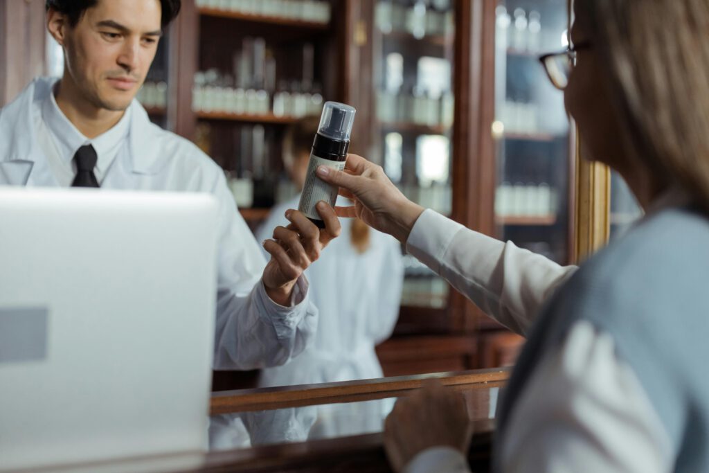 pexels-photo-8657358-8657358 A pharmacist in a white uniform hands medication to a customer across the counter.